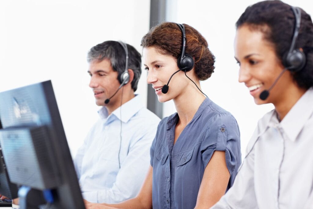 Three people, wearing headsets, sit in a row working on desktop computers at Central Station. This bustling hub might be a customer support or call center environment.