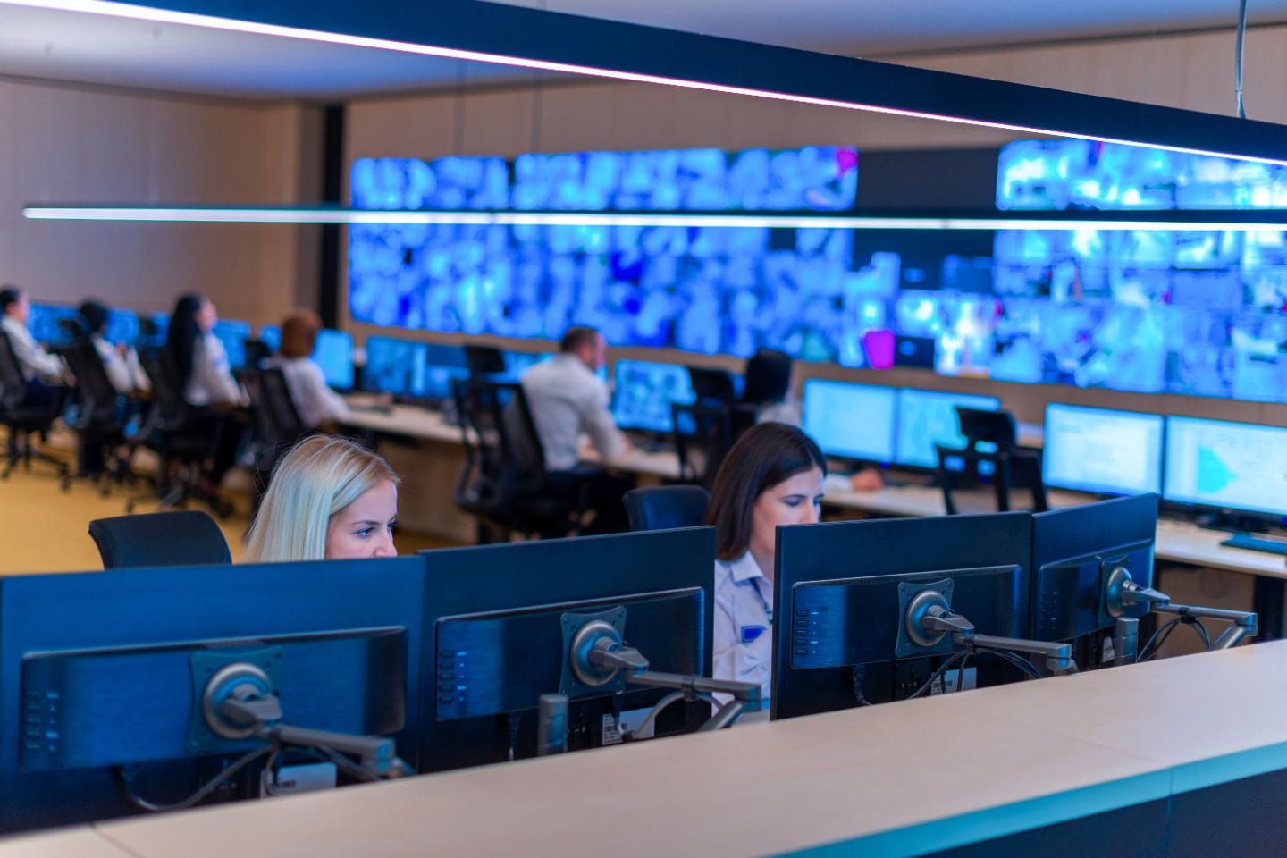 A control room with people seated at workstations monitors multiple computer screens, ensuring the seamless operation of a sophisticated home security system.